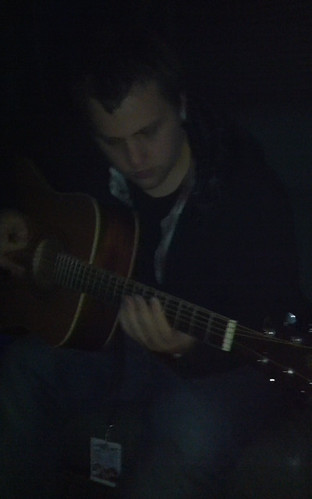 Timmy playing the guitar in the darkness on the bus
